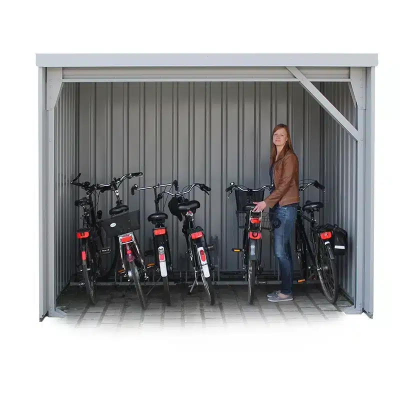 Open stalen fietsenstalling met meerdere fietsen op rij, een vrouw zet haar fiets in een geïntegreerd fietsenrek.