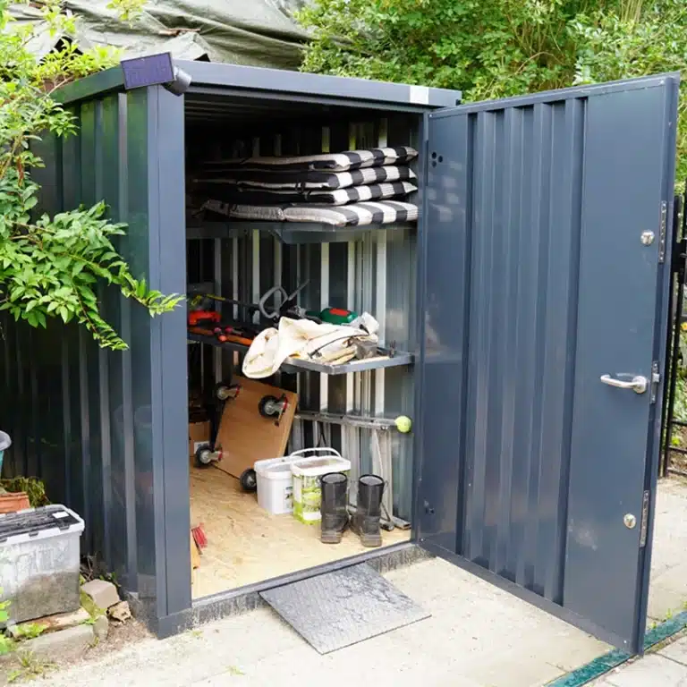 Antracieten tuincontainer in de tuin geplaats met tuinspullen opgeslagen