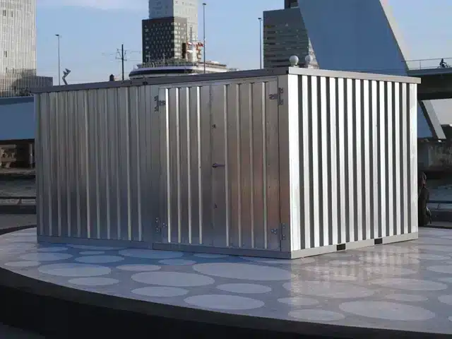 Foto van een demontabele container gekoppelde aan een andere demontabele container met uitzicht op de Erasmusbrug in Rotterdam