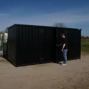 Man opent zwarte demontabele container van 5x2 meter met dubbele deuren op een buitenlocatie