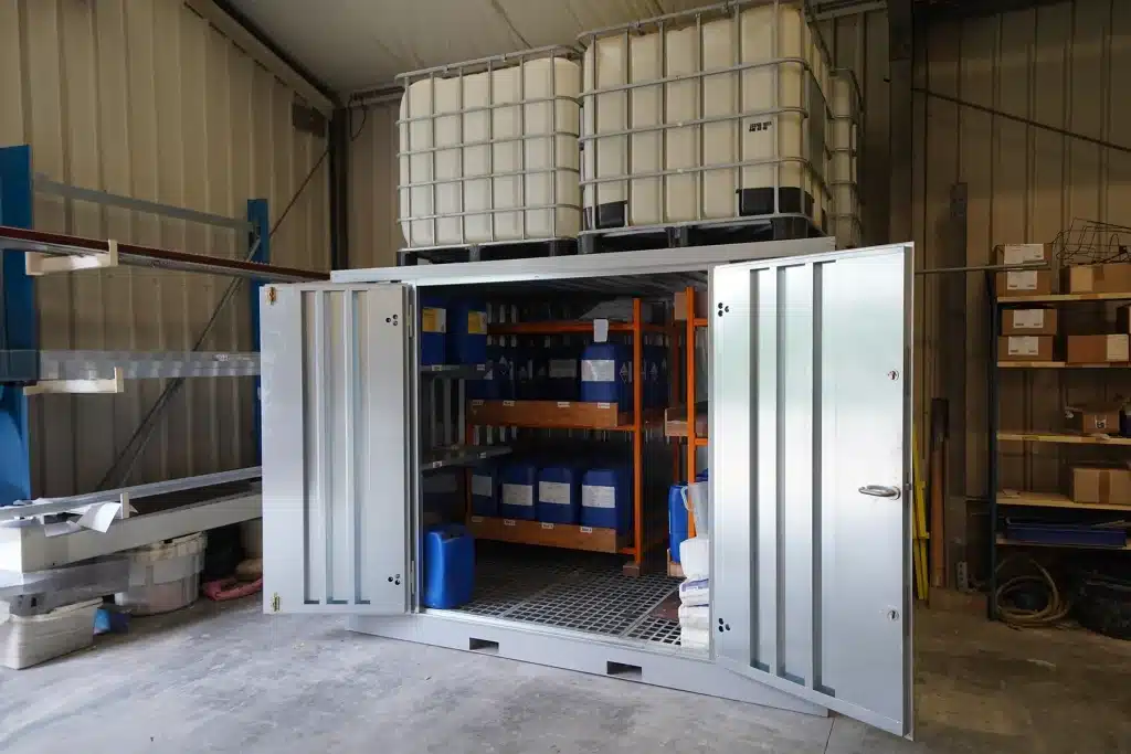 Demontabele chemische opslagcontainer met lekbak en stellingrek, geplaatst in een loods