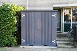 Grijze opslagcontainer voor de deur in de voortuin