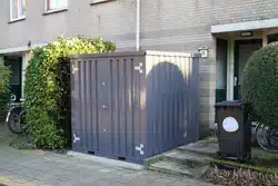 Grijze container in de voortuin met dichte dubbele deuren