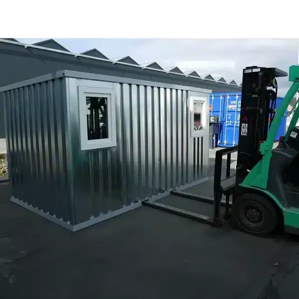 Geïsoleerde stalen unit met ramen wordt verplaatst met een heftruck op een industrieterrein.