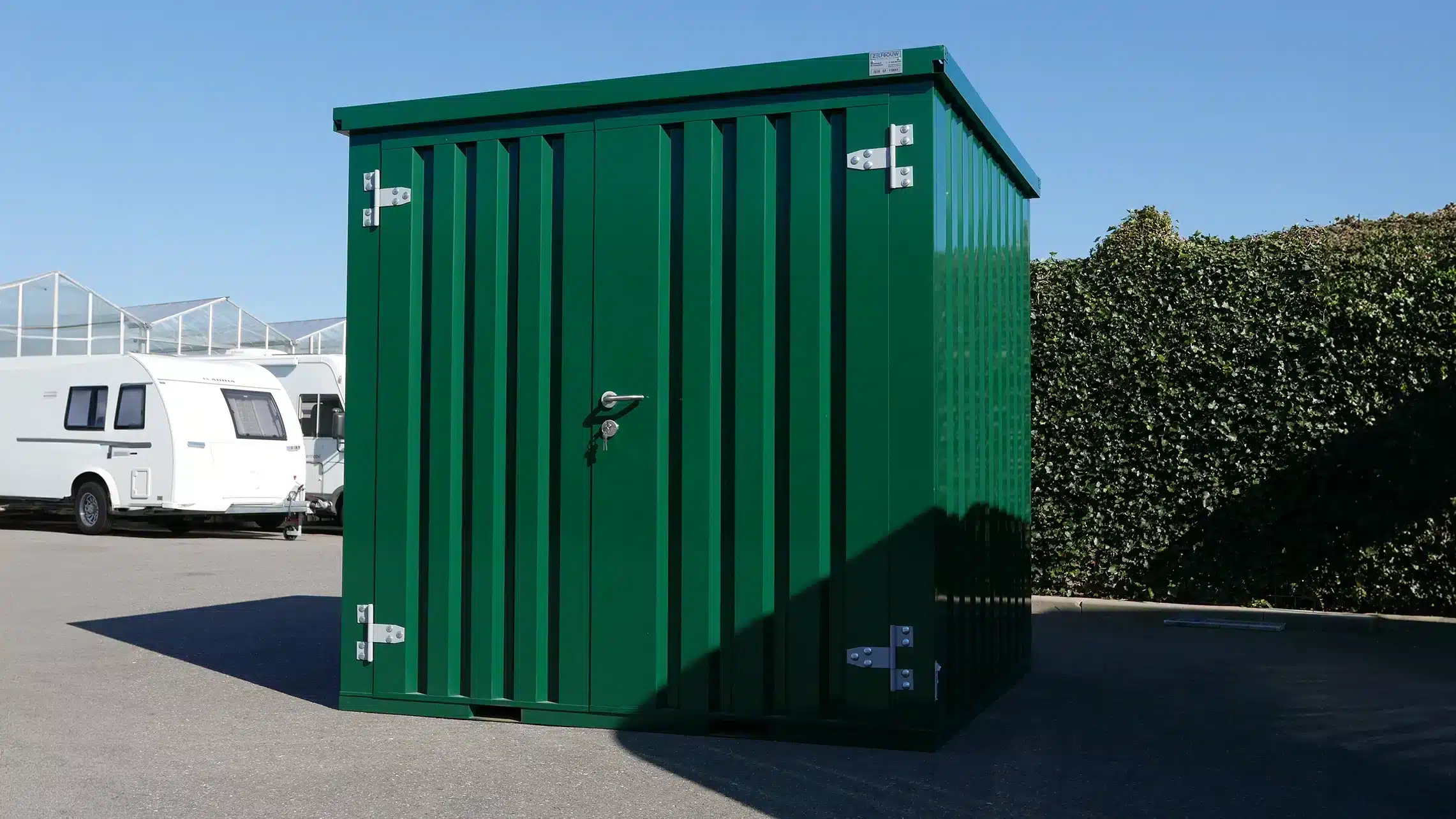 Groene opslagcontainer in de tuin. 2x2 in de kleur RAL 6000 met een dubbele deur aan de korte zijde