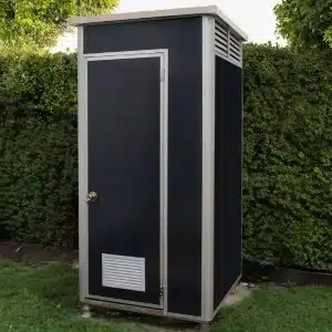 Prefab toiletunit 1,1 x 1,1 meter met ventilatie en afsluitbare deur, geplaatst in een groene tuin.