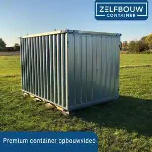 Een metalen container in het midden van een groen grasveld. Op de achtergrond staan bomen. Er is een heldere blauwe lucht.