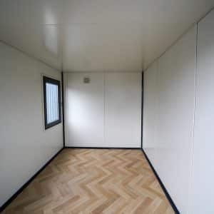 Interieur van een kantoorunit 3x2 meter met een modern houten vloerpatroon en witte wanden.